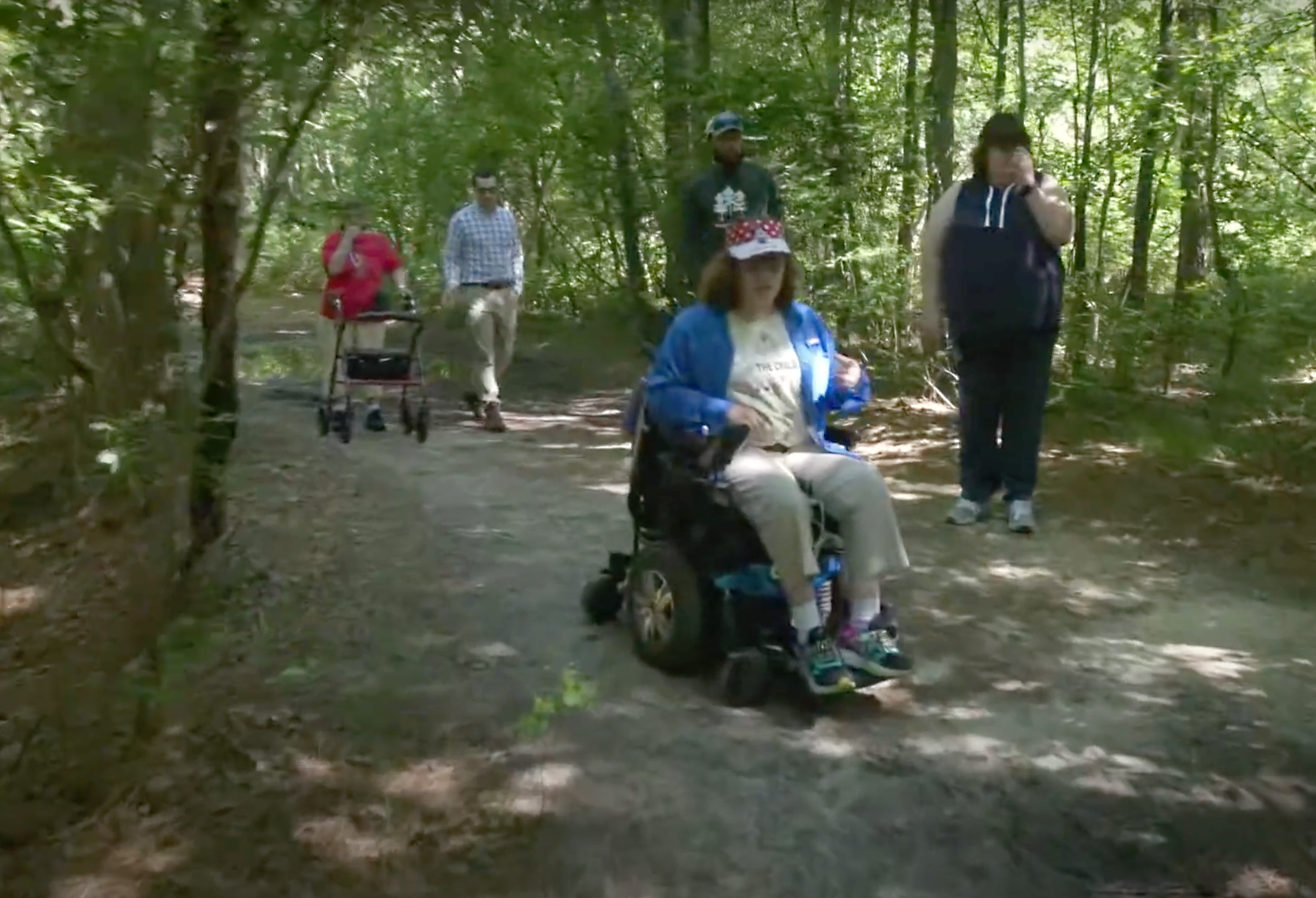 A group enjoying a trail, including a wheelchair user and person using a walker