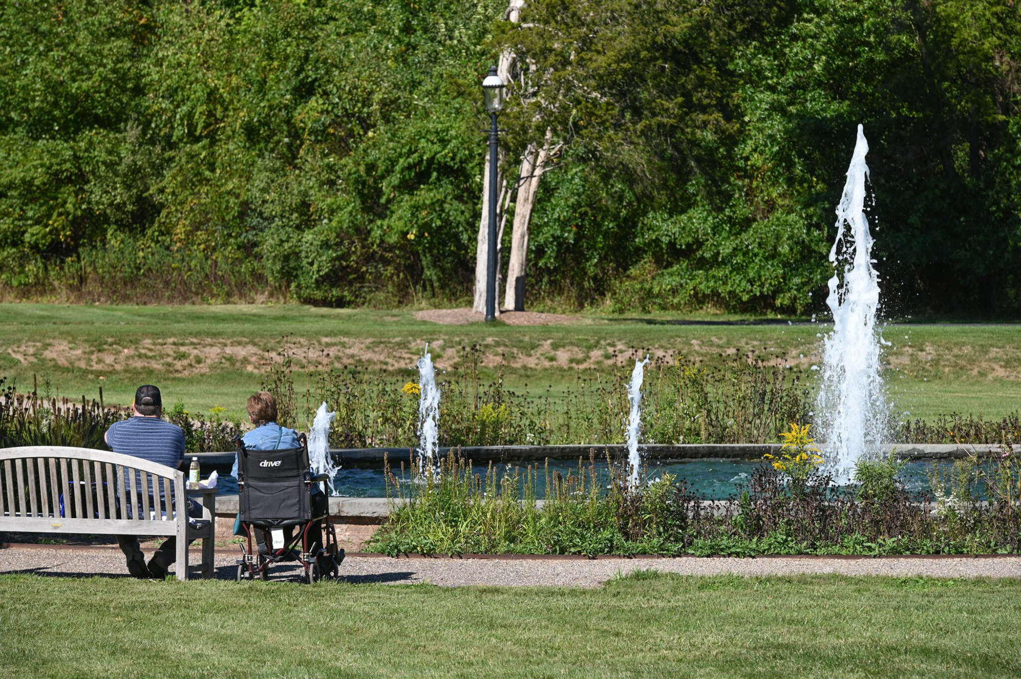 A wheelchair user and companion enjoy a water fountain feature together